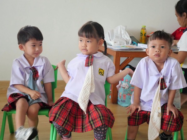 Three children on chairs, each holding their own cloth
