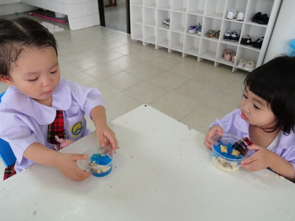 Two children eating at a table, shoe racks behind them