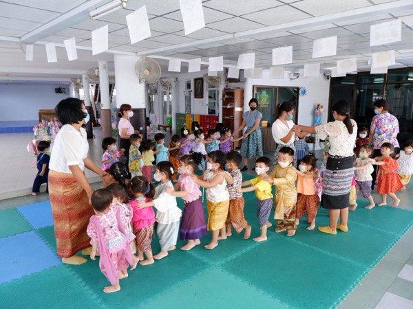 The whole school in Thai dress, holding hands in a circle in the hall