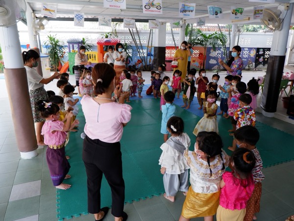 Children in Thai dress standing in a ring with a teacher in the middle
