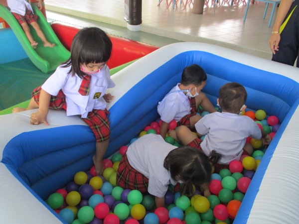 Children sitting and playing in the ball pit, the slide behind them