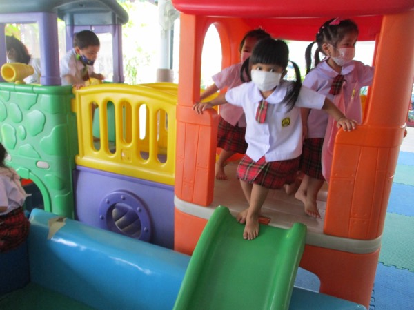 Three children on the plastic climbing frame, one at the top of the slide