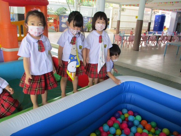 Three children waiting their turn at the edge of the ball pit